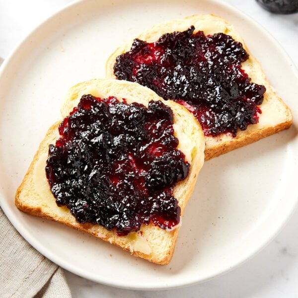 White plate with two slices of bread slathered with jam and butter.
