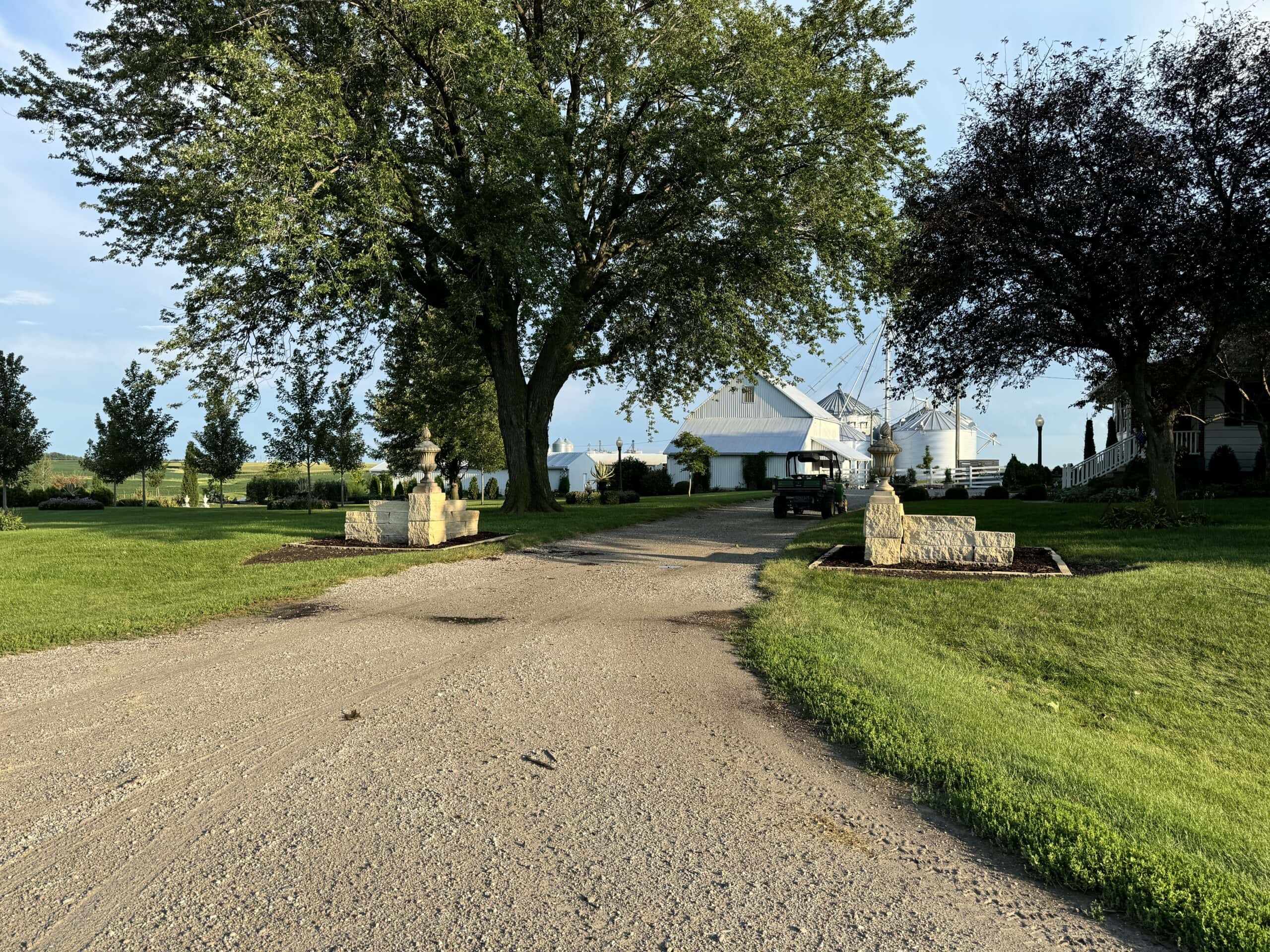 Front driveway with two new columns lining the side of the driveway with barns in the background.