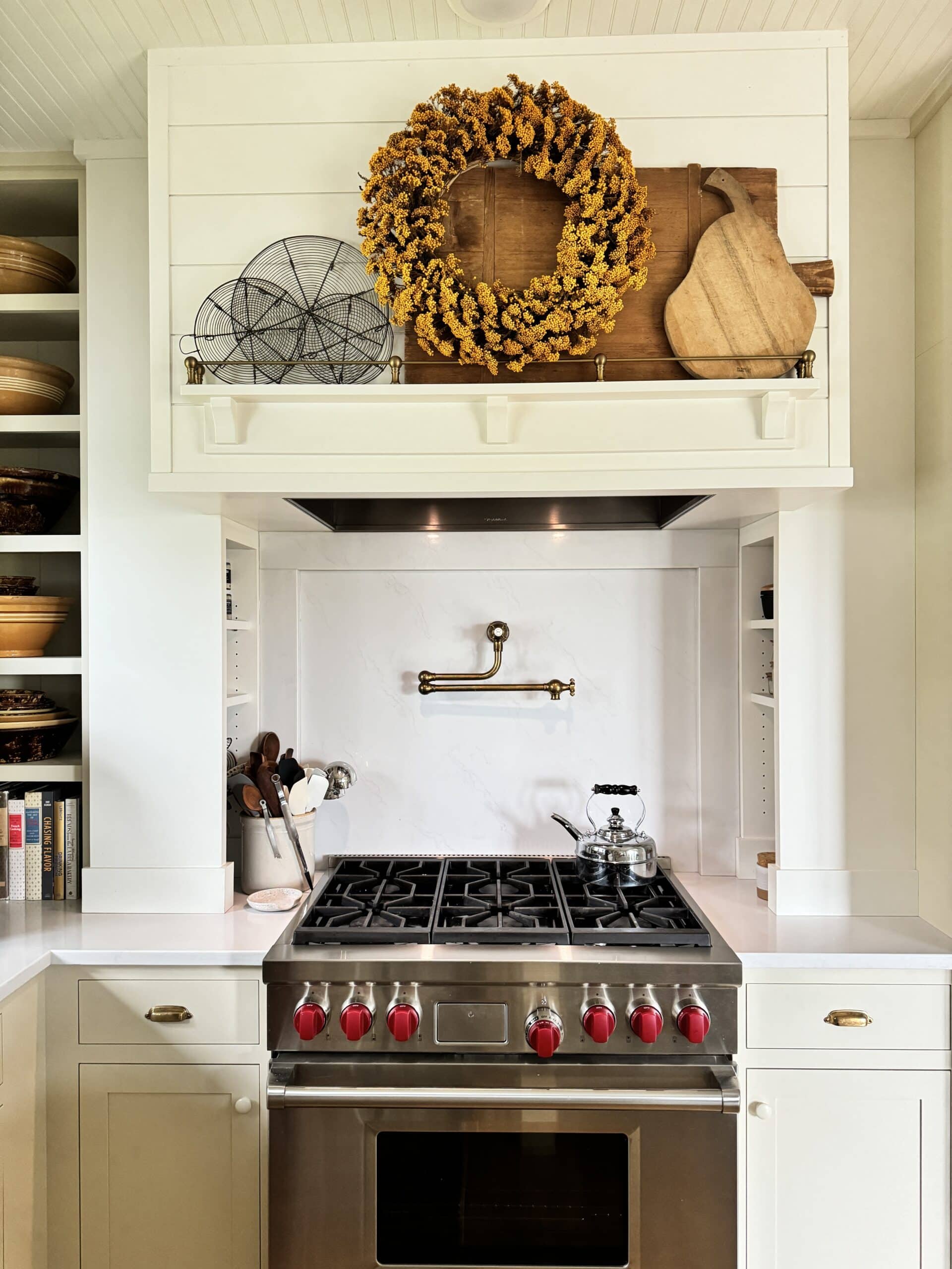 Hood above range in kitchen with yellow fall-themed wreath hanging.