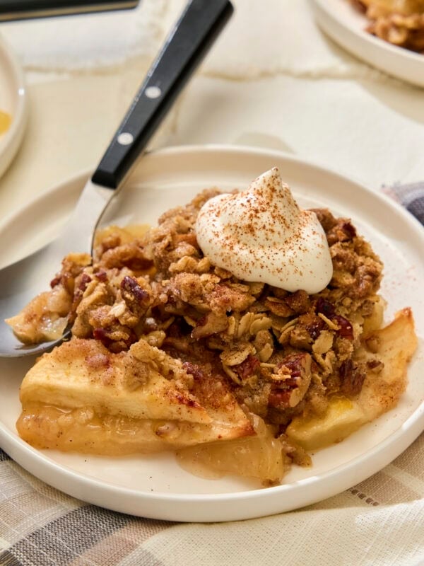 Serving of apple crisp with whipped cream on top.