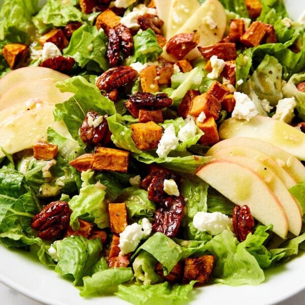 Large white bowl filled with apple & sweet potato salad with feta and crunchy lettuce.