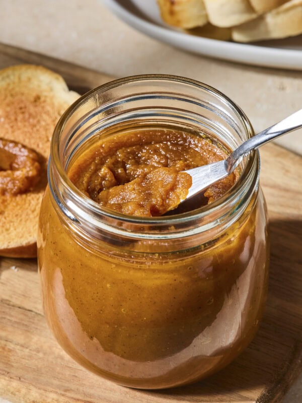 Jar with pumpkin butter with a knife scooping out a serving.
