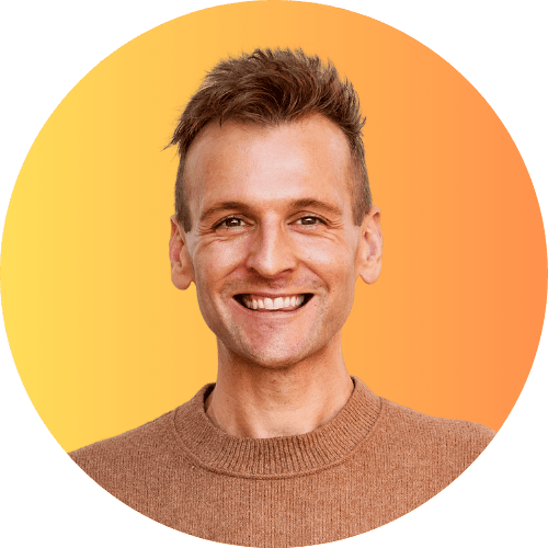 Kaleb Wyse wearing a brown sweater standing in front of an orange ombre background.