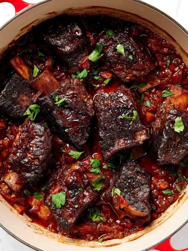 Short ribs garnished with parsley in a dutch oven.