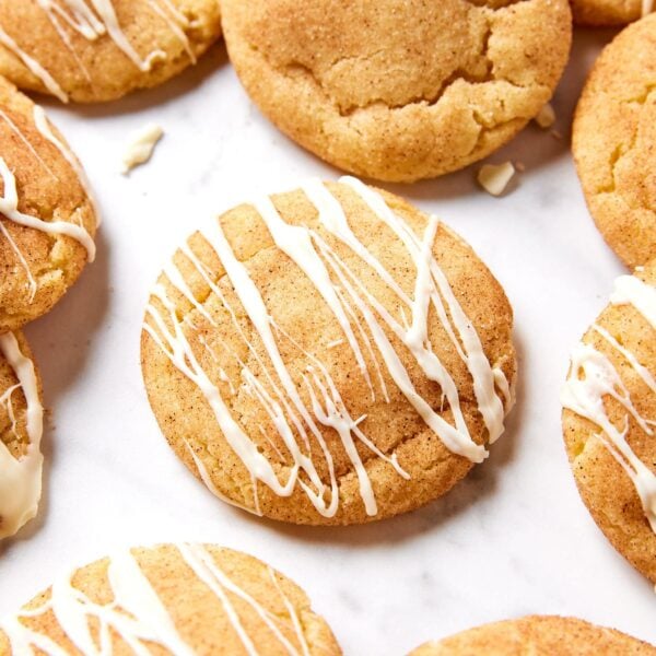White marble surface with brown butter Snickerdoodle cookie recipe with white chocolate drizzled on top.