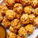 White platter filled with sweet potato puffs with fresh herbs sprinkled on top.
