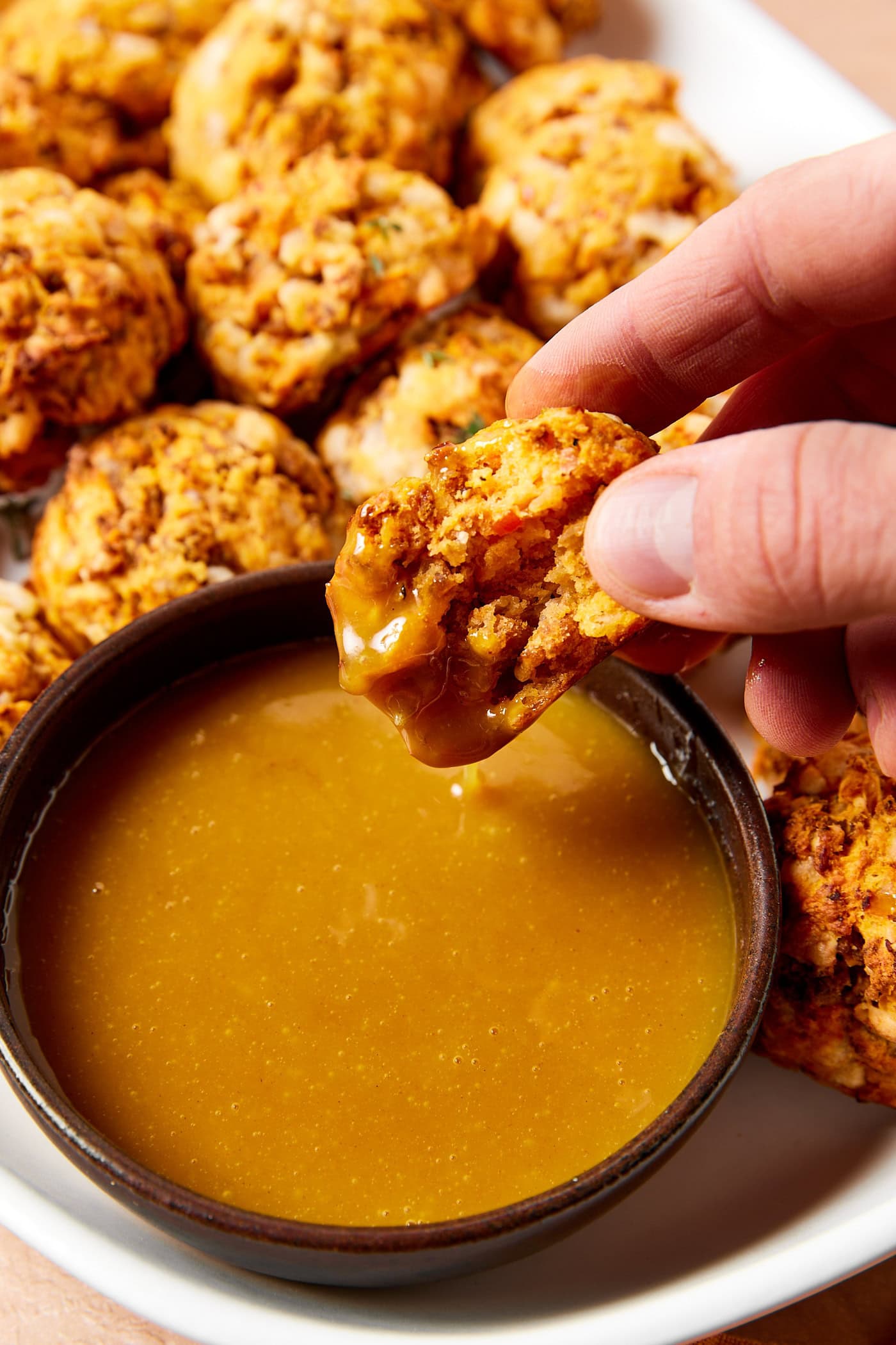 Dipping a sweet potato and sausage bite into honey Dijon mustard.