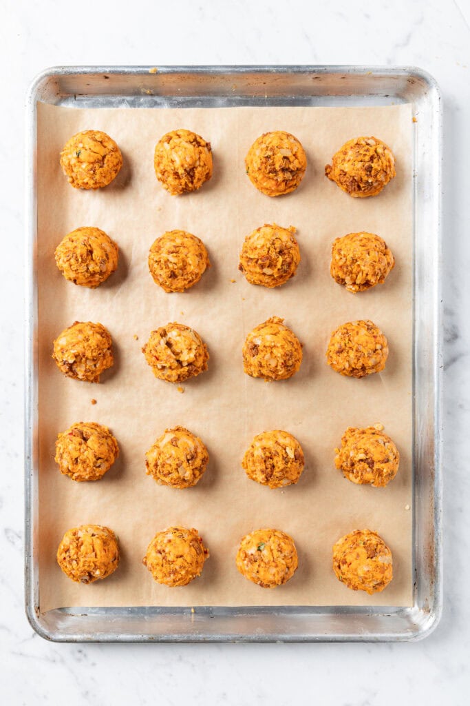 Balled sweet potato puffs sit on a baking sheet prior to cooking.