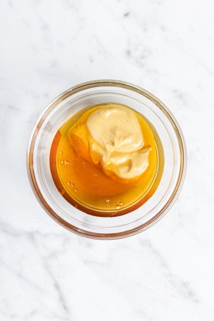 Equal parts Dijon mustard and honey in a bowl prior to being mixed.