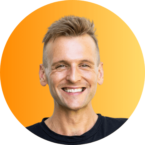 Kaleb Wyse wearing a black shirt standing in front of an orange ombre background.