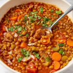 Sausage and lentil soup in a bowl garnished with parsley.