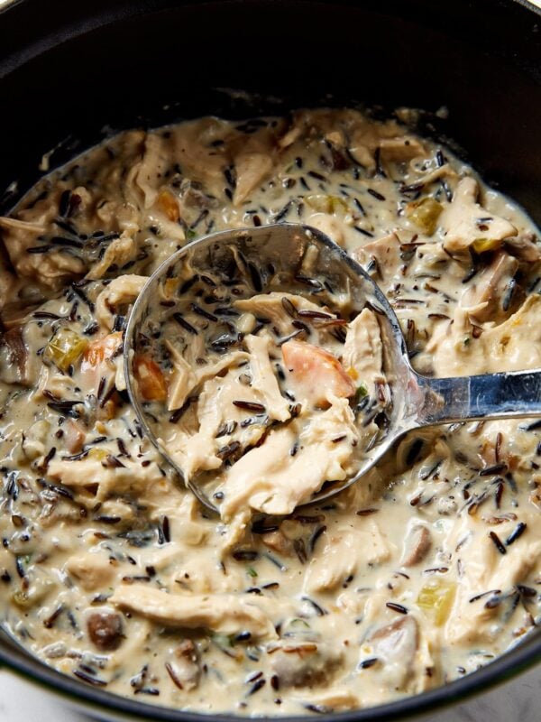 A ladle in a pot of chicken and wild rice soup.