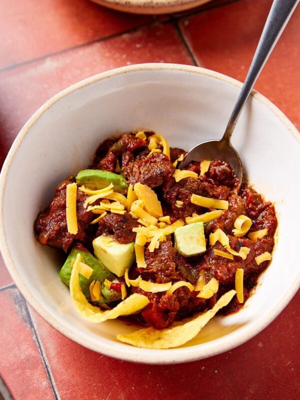 A bowl of chili con carne covered with toppings.