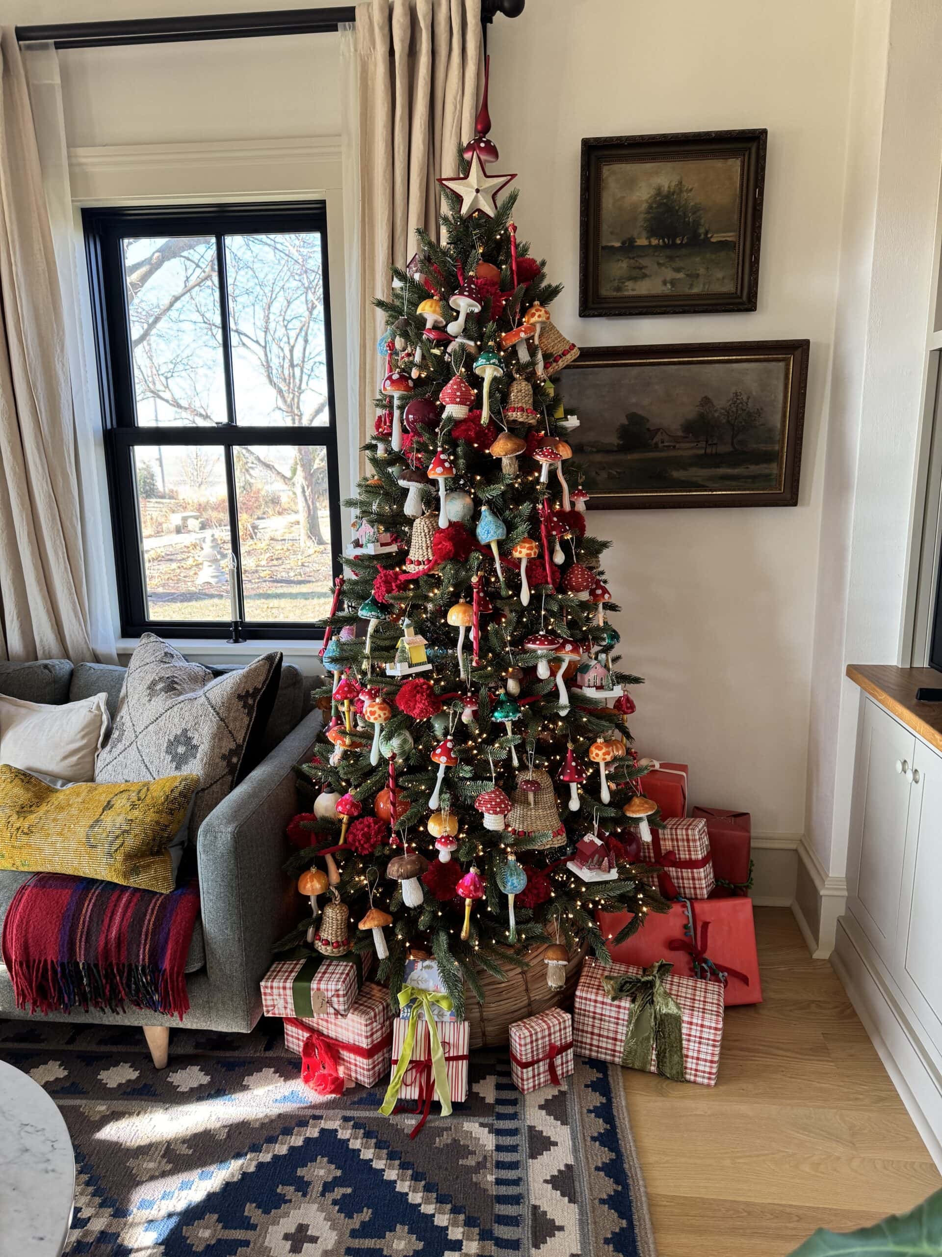 Christmas tree decorated with mushrooms in a living room with a sofa to the side.