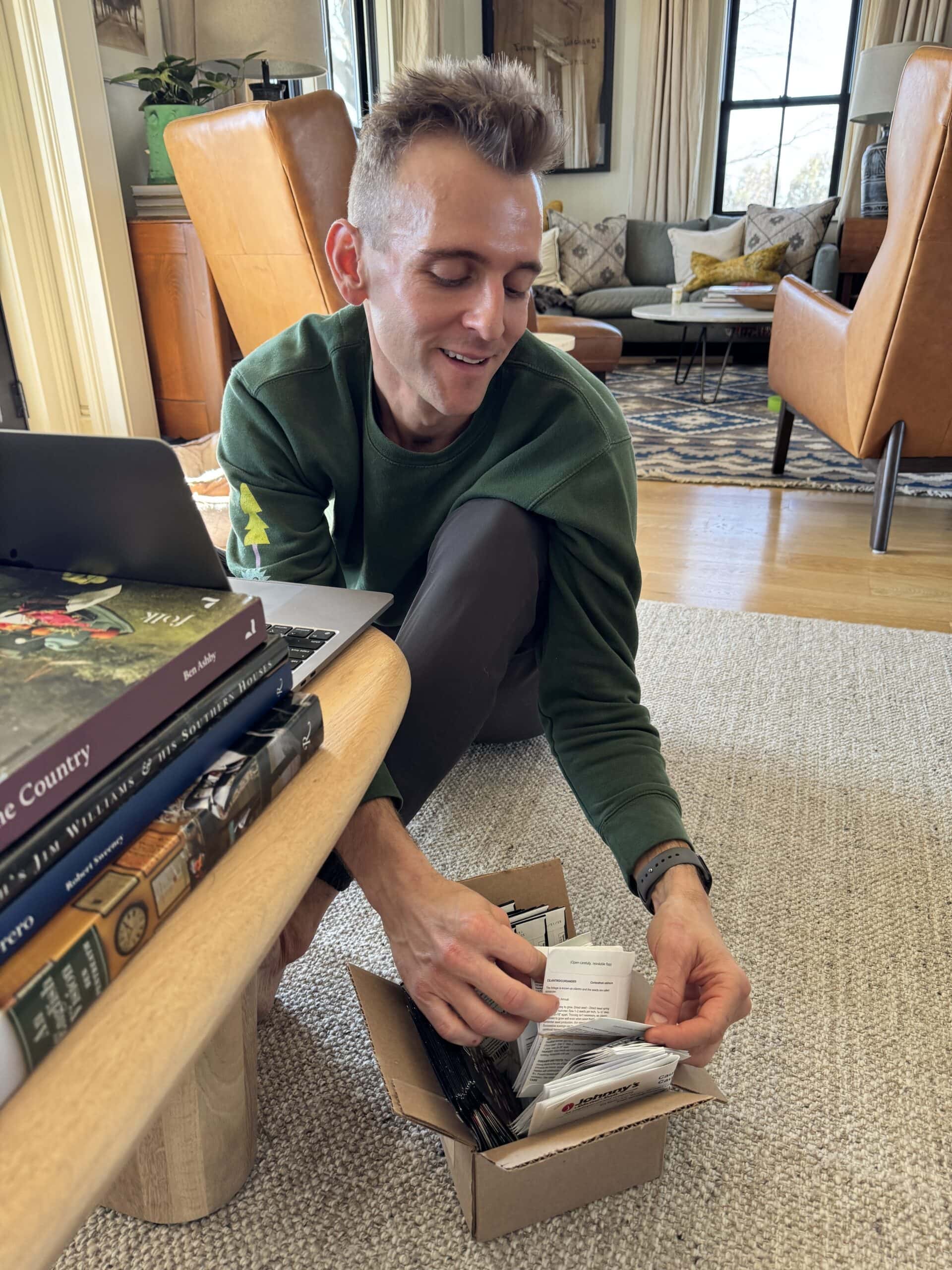 Kaleb Wyse sitting on floor sorting through seeds for vegetables to plant in the spring.