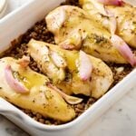 Honey mustard chicken breast with lentils in a baking dish.