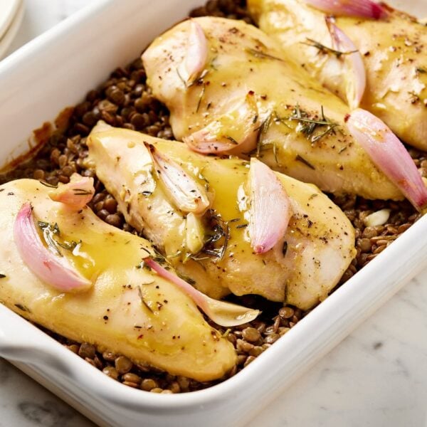 Honey mustard chicken breast with lentils in a baking dish.