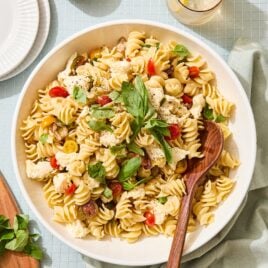 White bowl filled with Caprese pasta salad with spoon scooping out a portion.