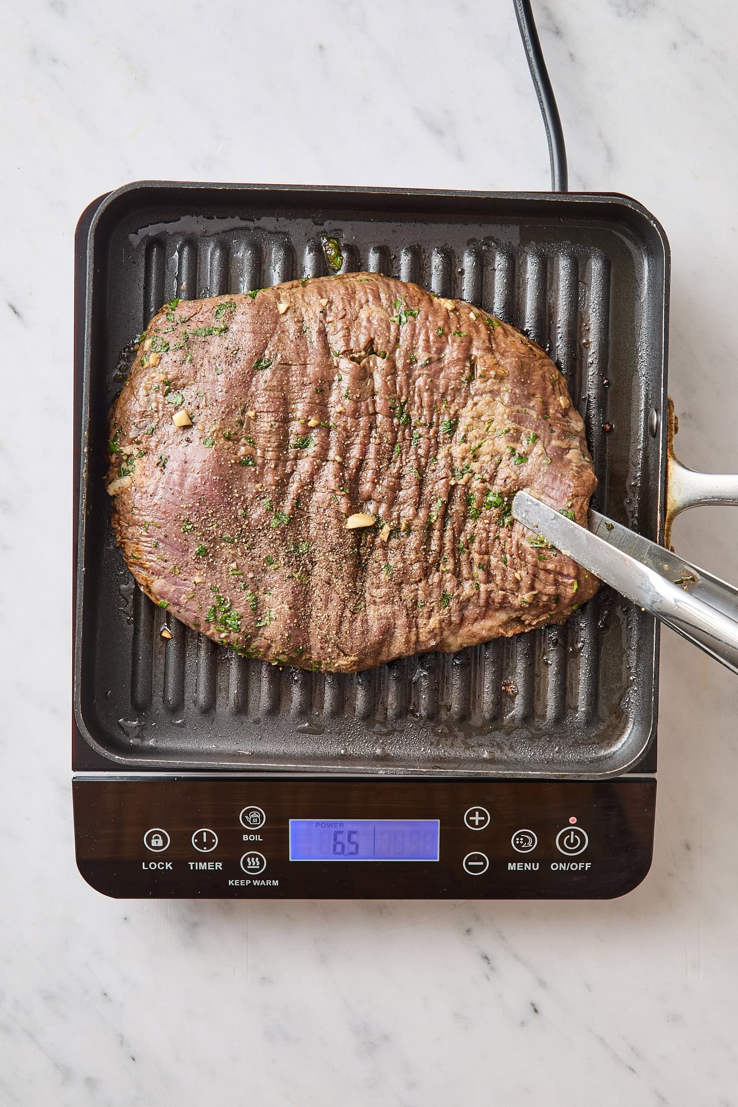 Raw marinated steak being grilled.