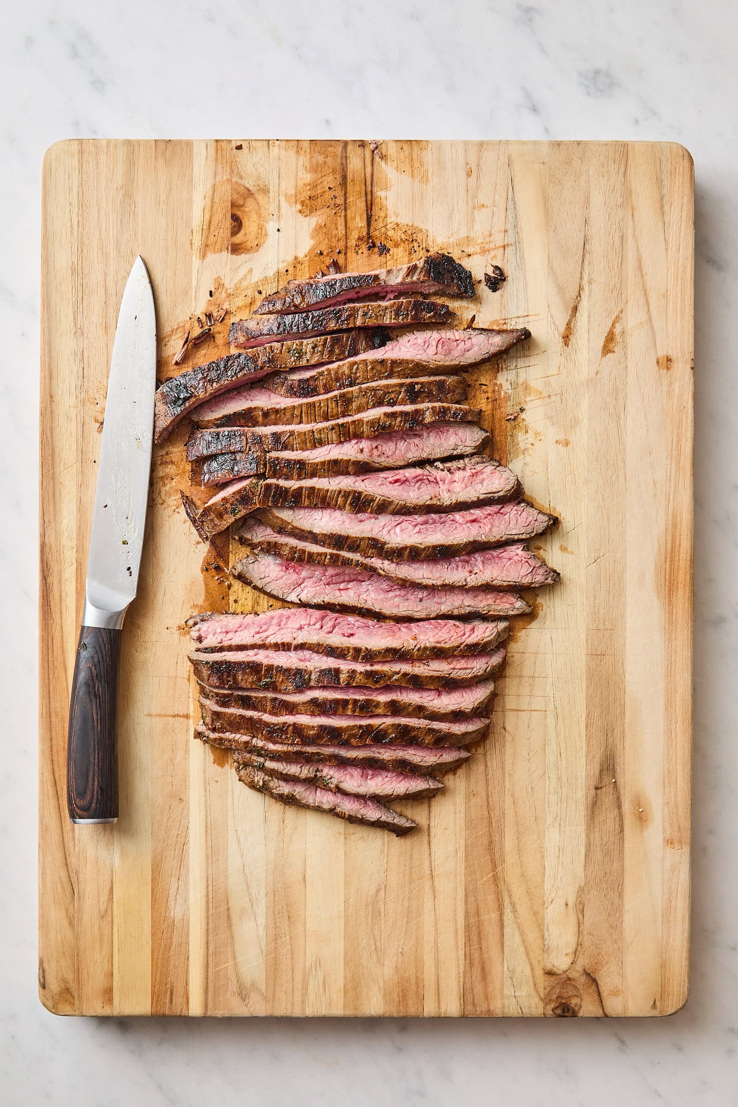 Wooden cutting board with slices of freshly grilled steak.