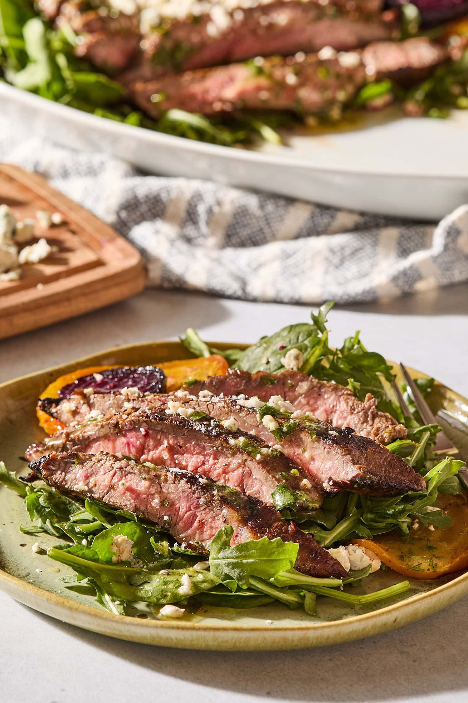 Plate with serving of steak and beet salad with crumbled blue cheese on top.
