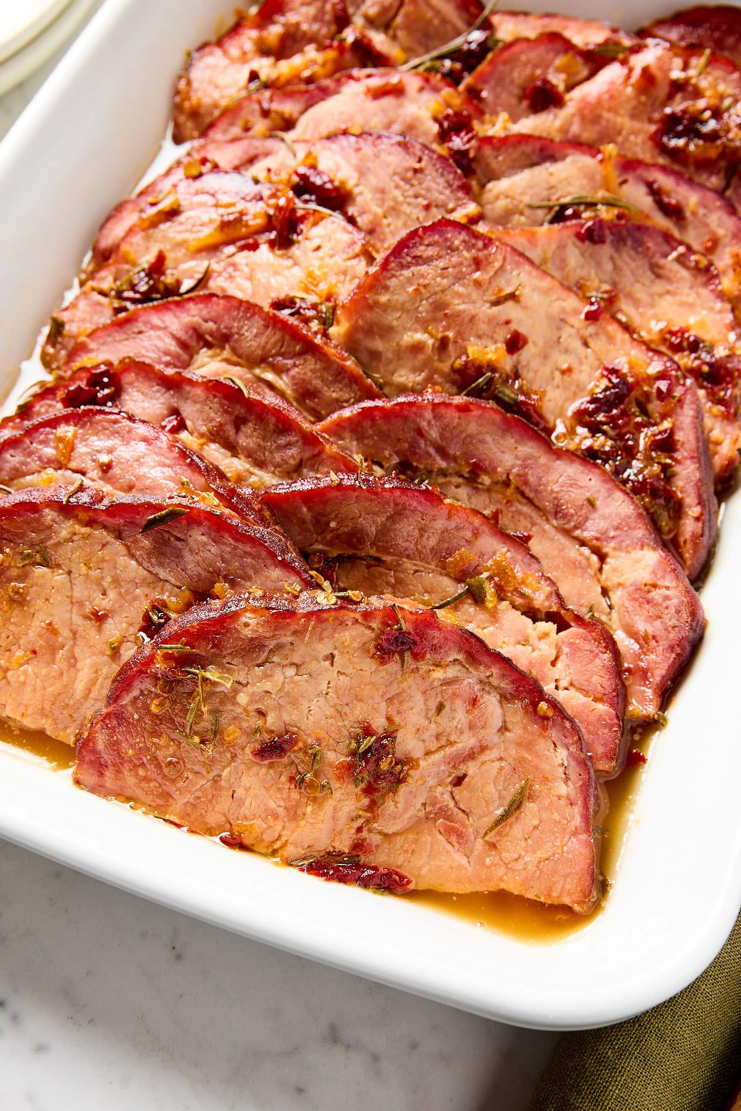 Slices of glazed ham sitting in a baking dish after cooking.