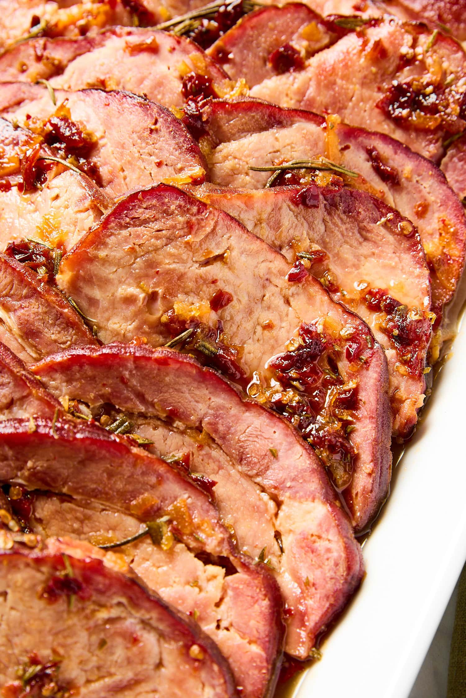Orange chipotle glaze sitting on ham slices after baking.
