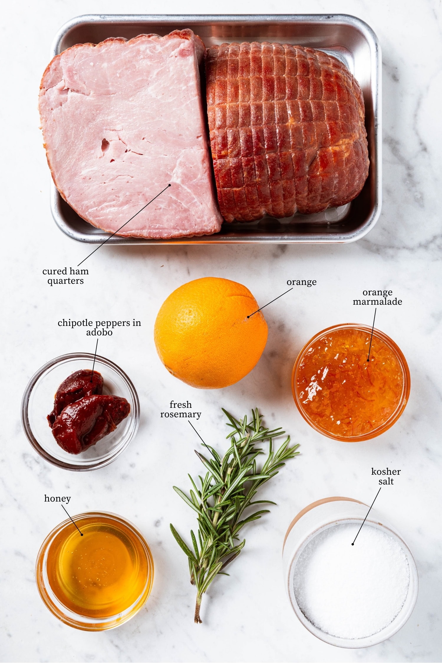 White marble surface with sliced glazed ham and ingredients needed for glaze.