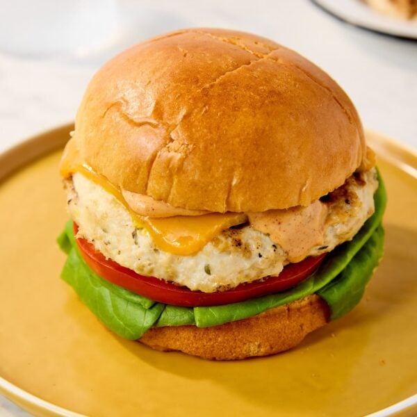A loaded chicken burger rests on a yellow plate.