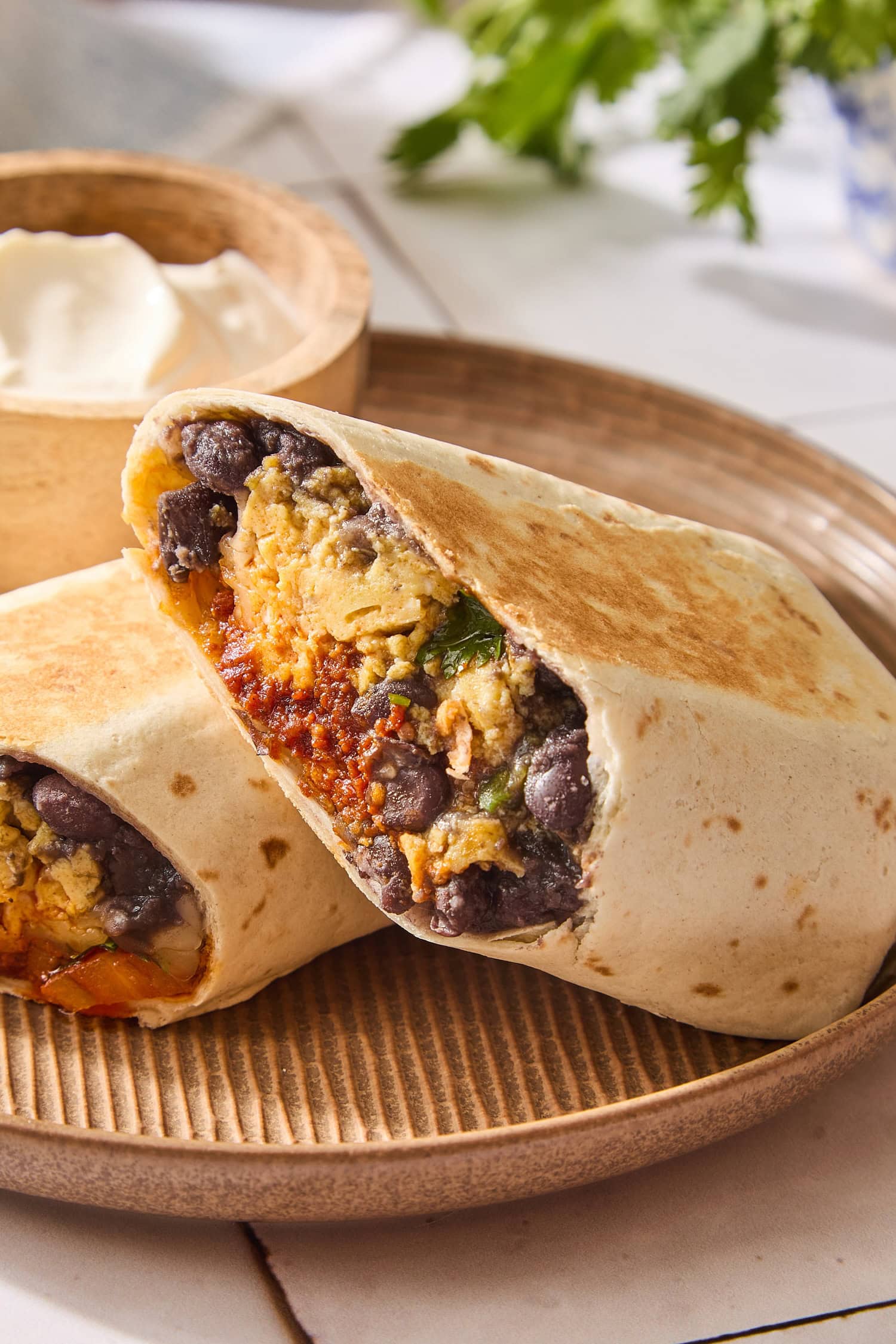 Two halves of a chorizo breakfast burrito sitting on top of each other on a plate.