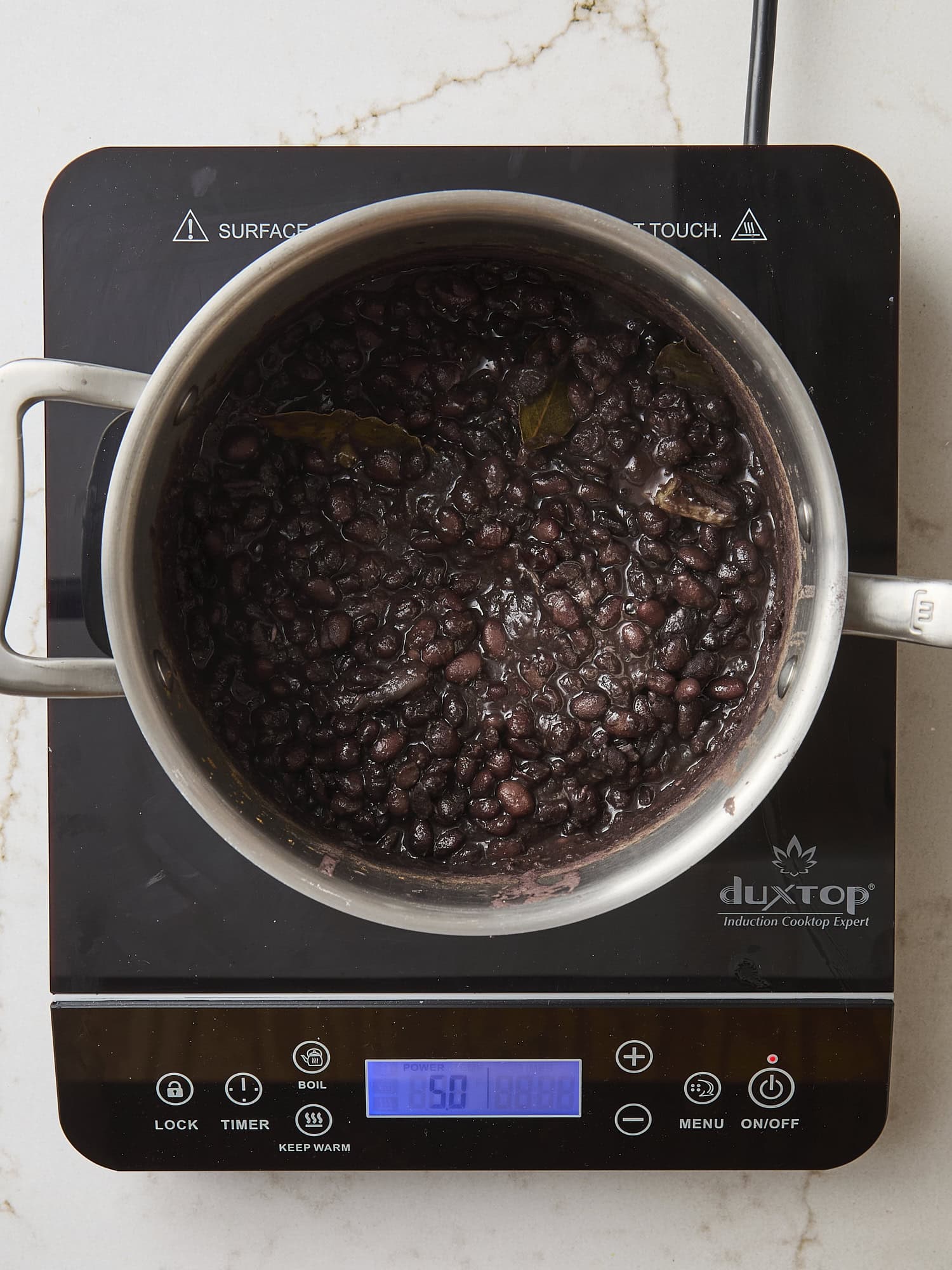 Pan with cooked black beans on a hot plate.
