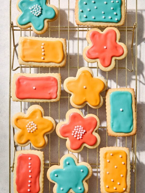 Cooling rack filled with frosted cutout sugar cookies in different colors.