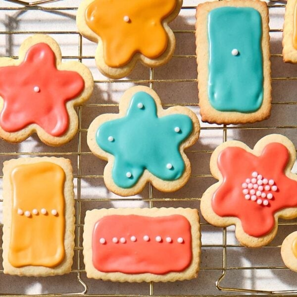 Cooling rack with frosted sugar cookies with orange, blue, and pink frosting.