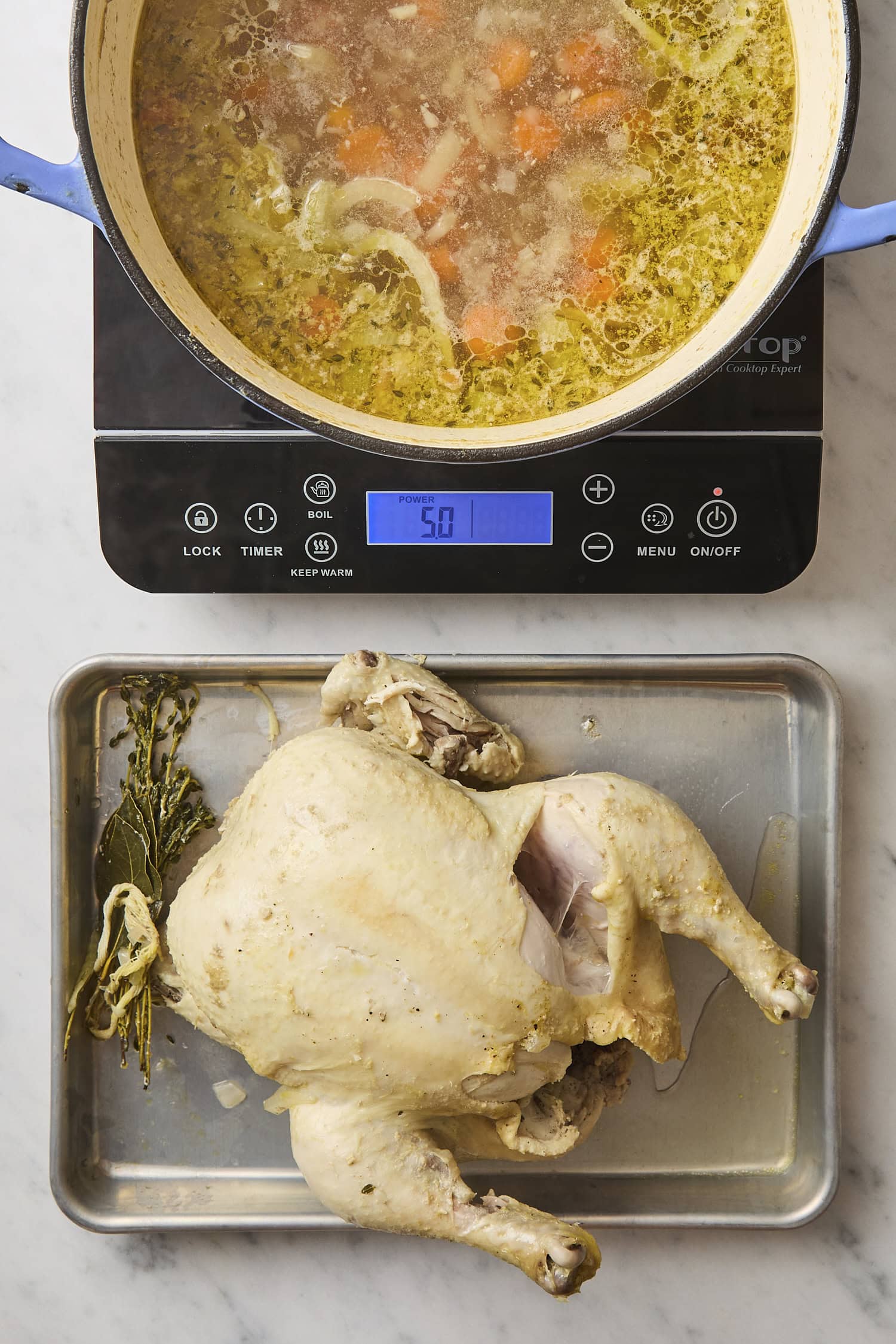 Cooked chicken on pan after being pulled from simmering soup.