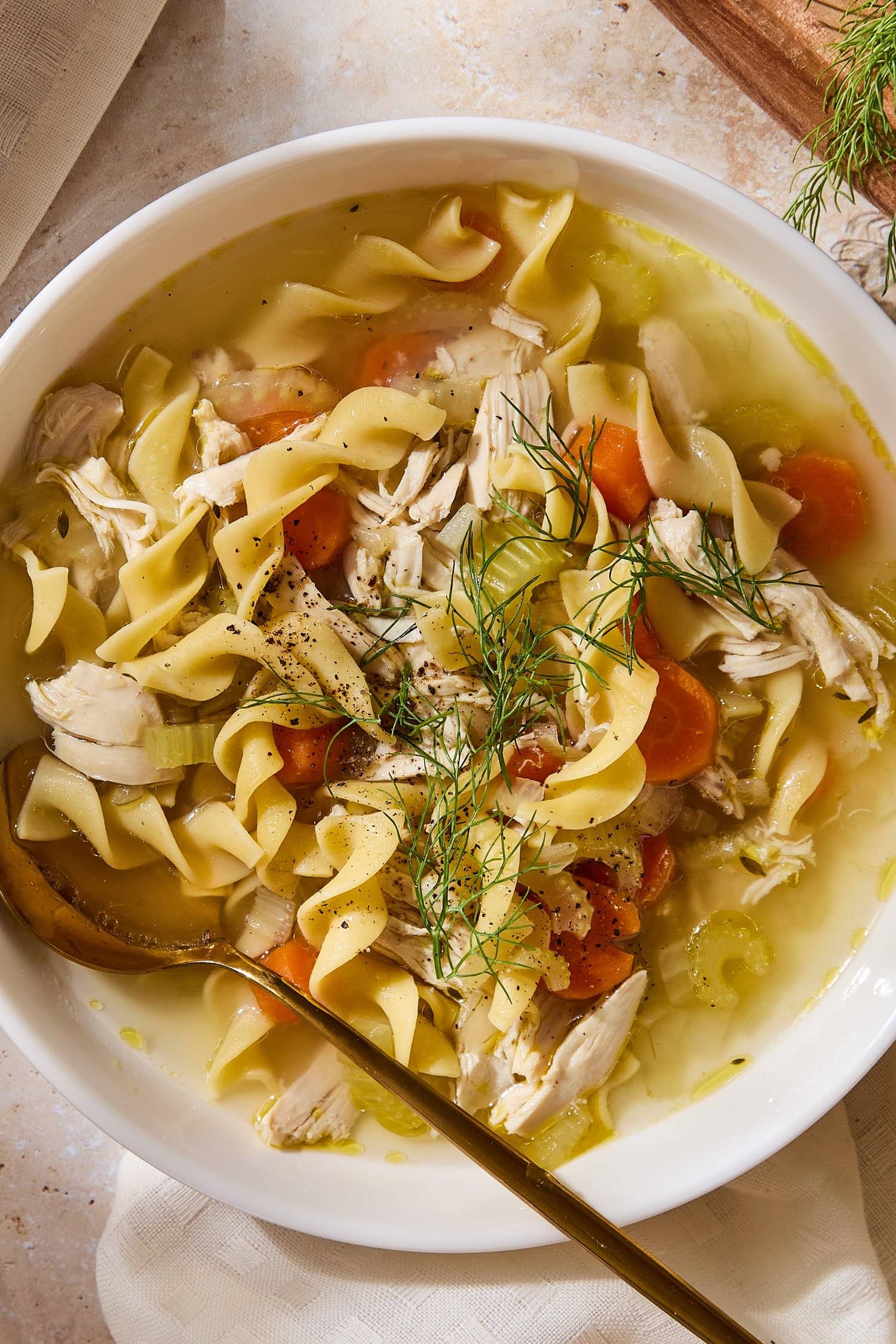 White bowl with chicken noodle soup with spoon resting in bowl.