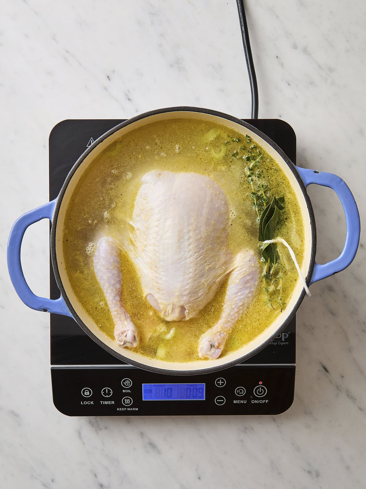 Pot with broth cooking with chicken and packet of herbs.