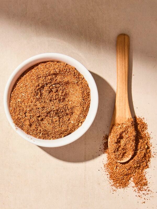 White bowl filled with homemade taco seasoning blend with more on spoon.