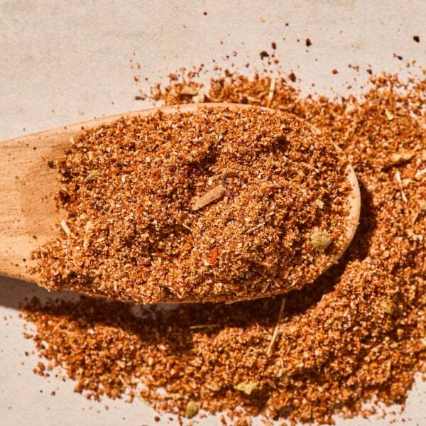 Wooden spoon with brown colored homemade taco seasoning blend in powder form.