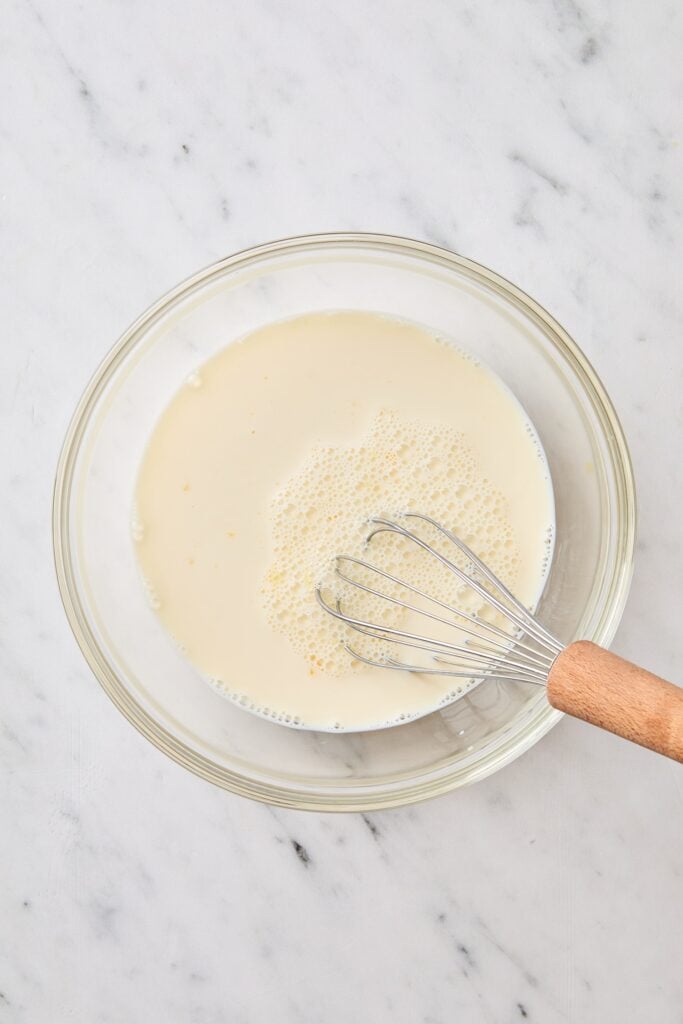 White marble surface with bowl of milk and eggs to make a vanilla pudding recipe.