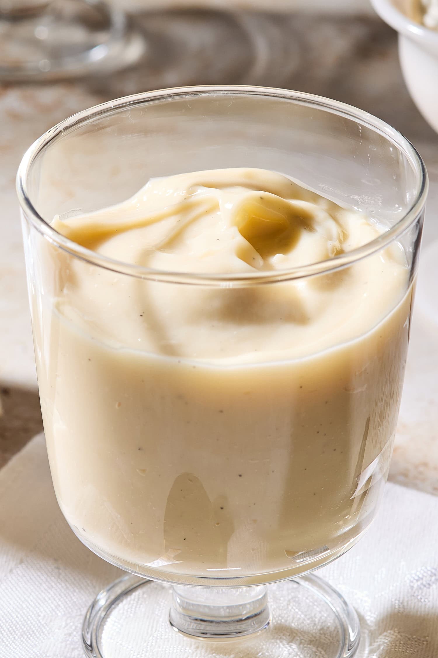 Glass filled with cream-colored vanilla pudding with a swirl on top.