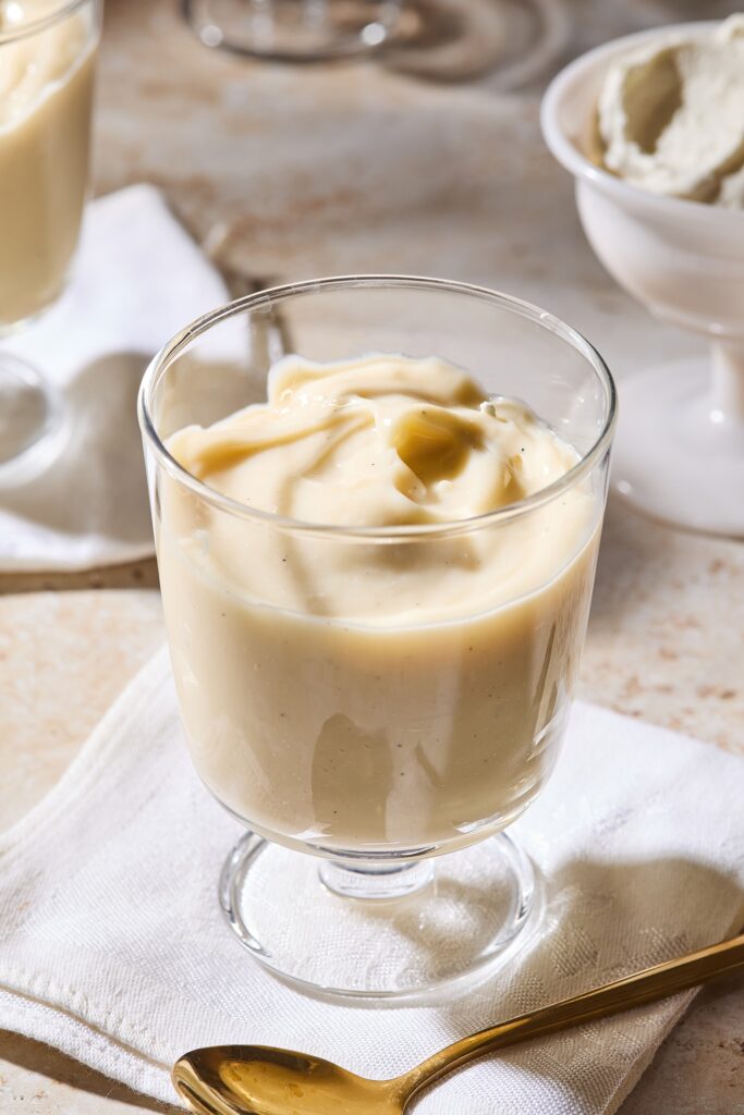 Dessert glass filled with homemade vanilla pudding with swirl on top.