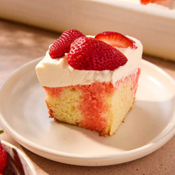 A slice of strawberry poke cake on a plate.