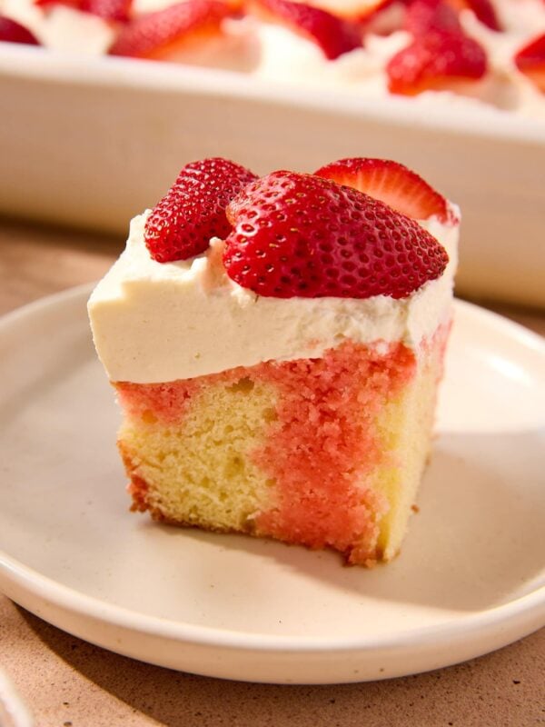 Slice of strawberry poke cake topped with strawberries.