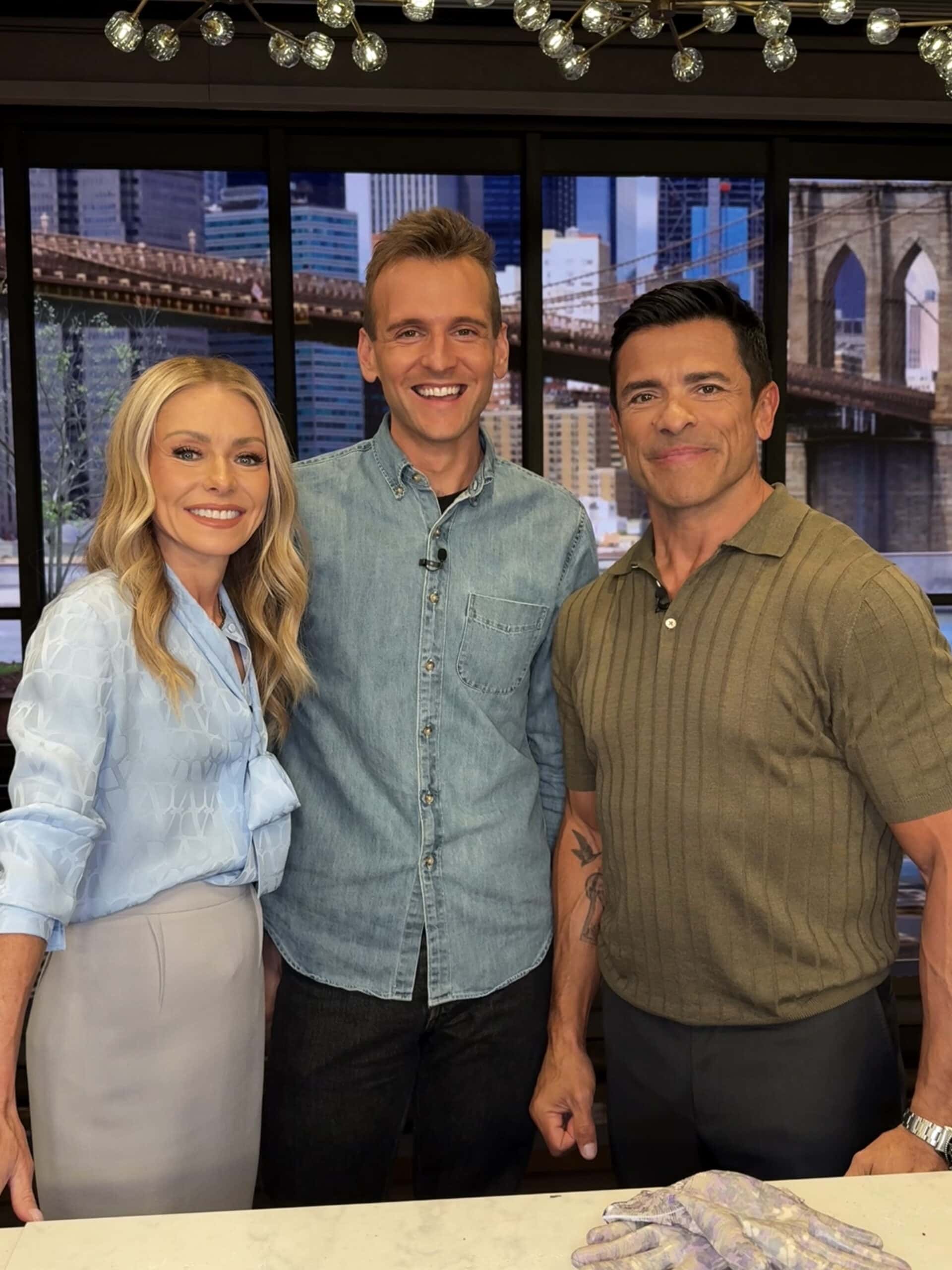 Kaleb Wyse standing with Kelly Ripa and Mark Consuelos in their studio.