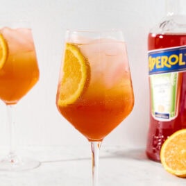 Aperol spritz with vibrant color in a wine glass on marble surface.