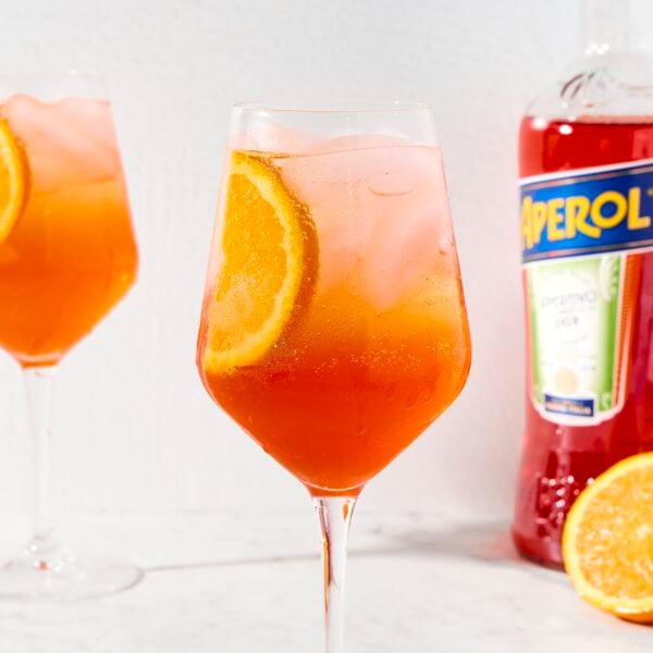 Aperol spritz with vibrant color in a wine glass on marble surface.