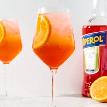 Wine glass with bright cocktail with slice of orange.