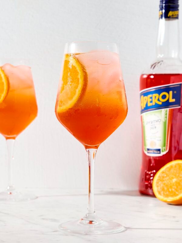 Wine glass with bright cocktail with slice of orange.