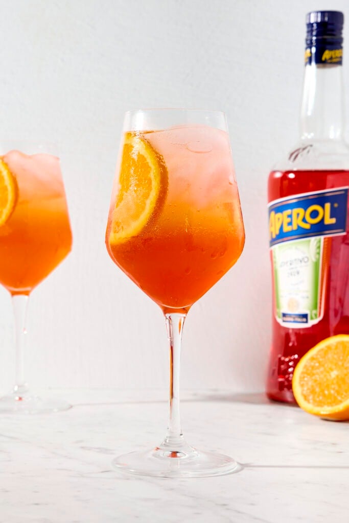 Wine glass with bright cocktail with slice of orange.