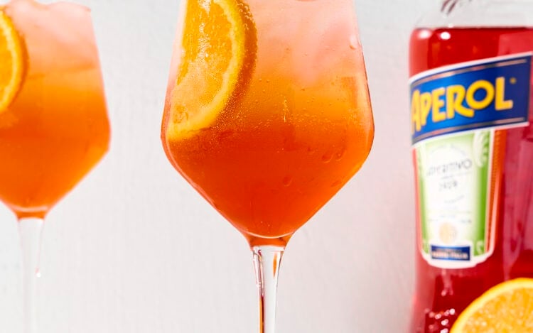 Wine glass with bright cocktail with slice of orange.